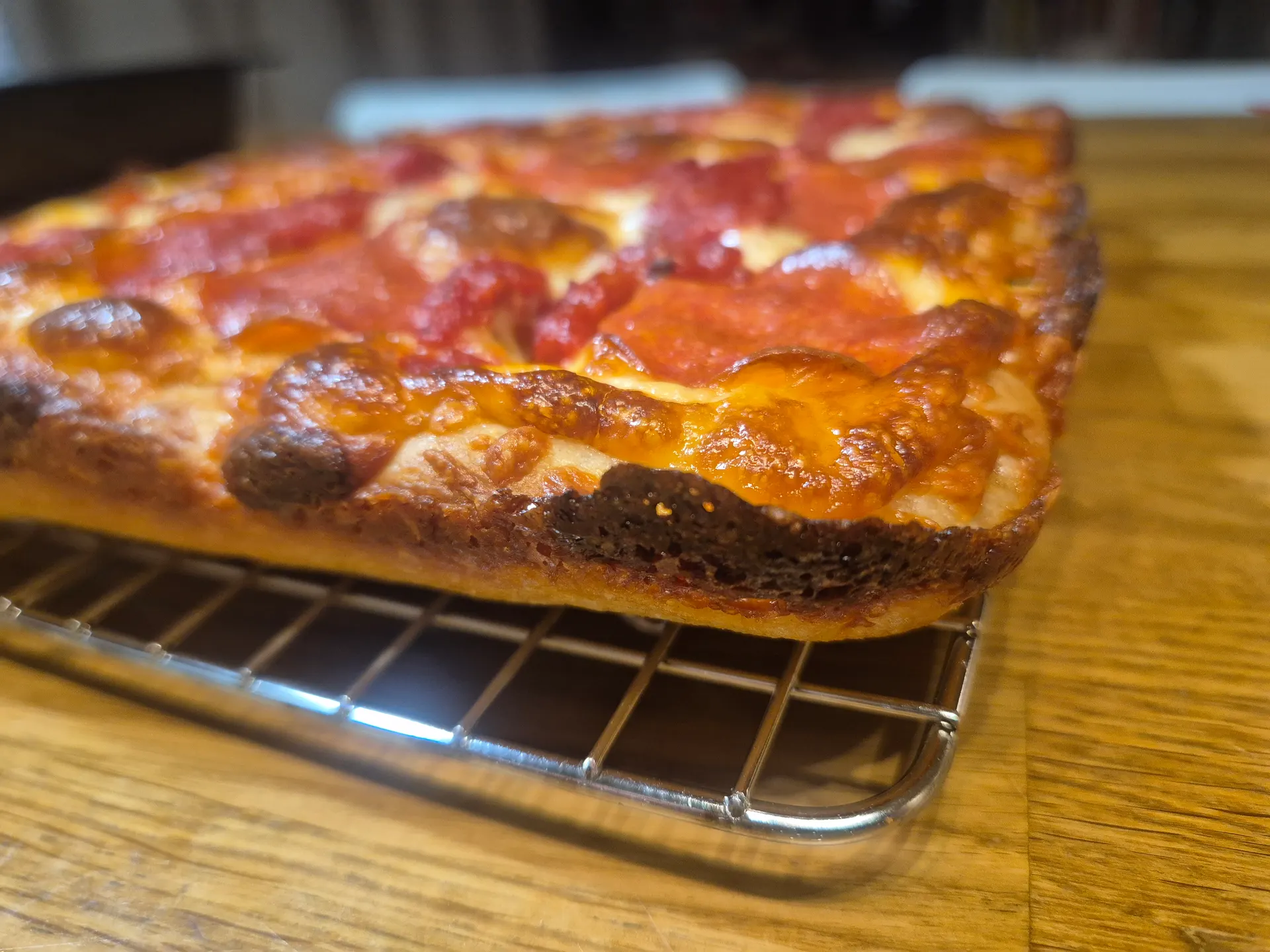 Close-up of the pizza edge: dark caramelised cheese crust